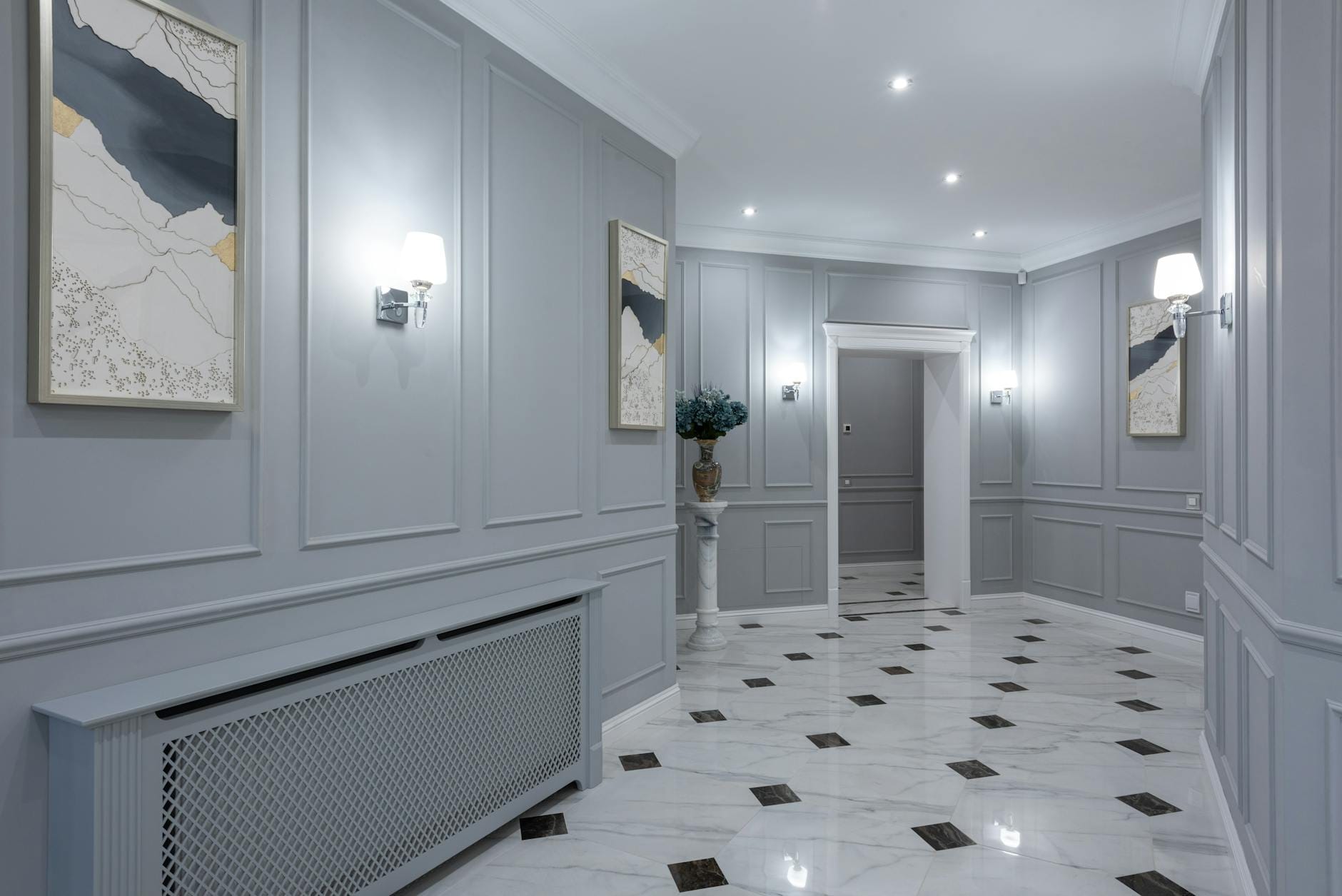 Nowoczesny korytarz z szarymi ścianami, obrazami i błyszczącą podłogą