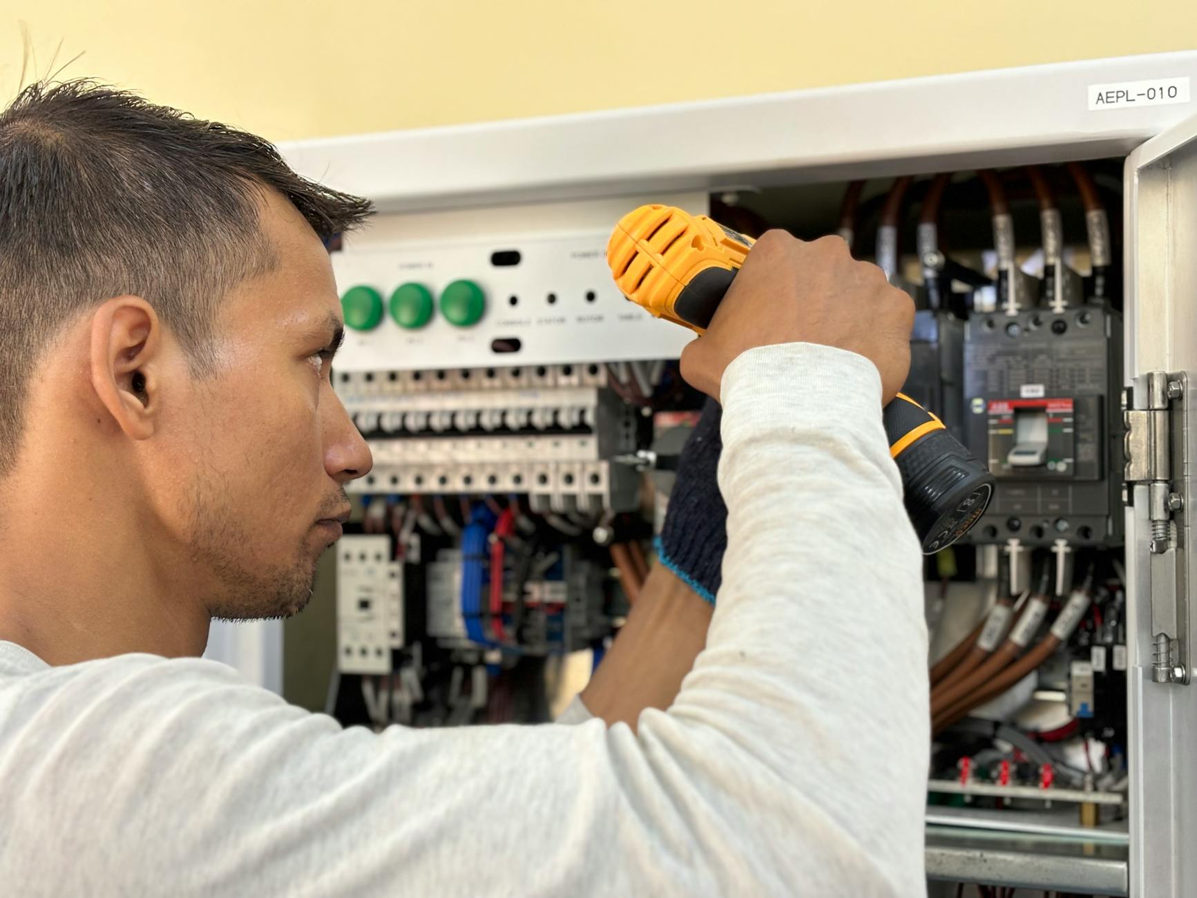 Elektryk wierci otwory przy domowej rozdzielnicy z wyłącznikami różnicowymi