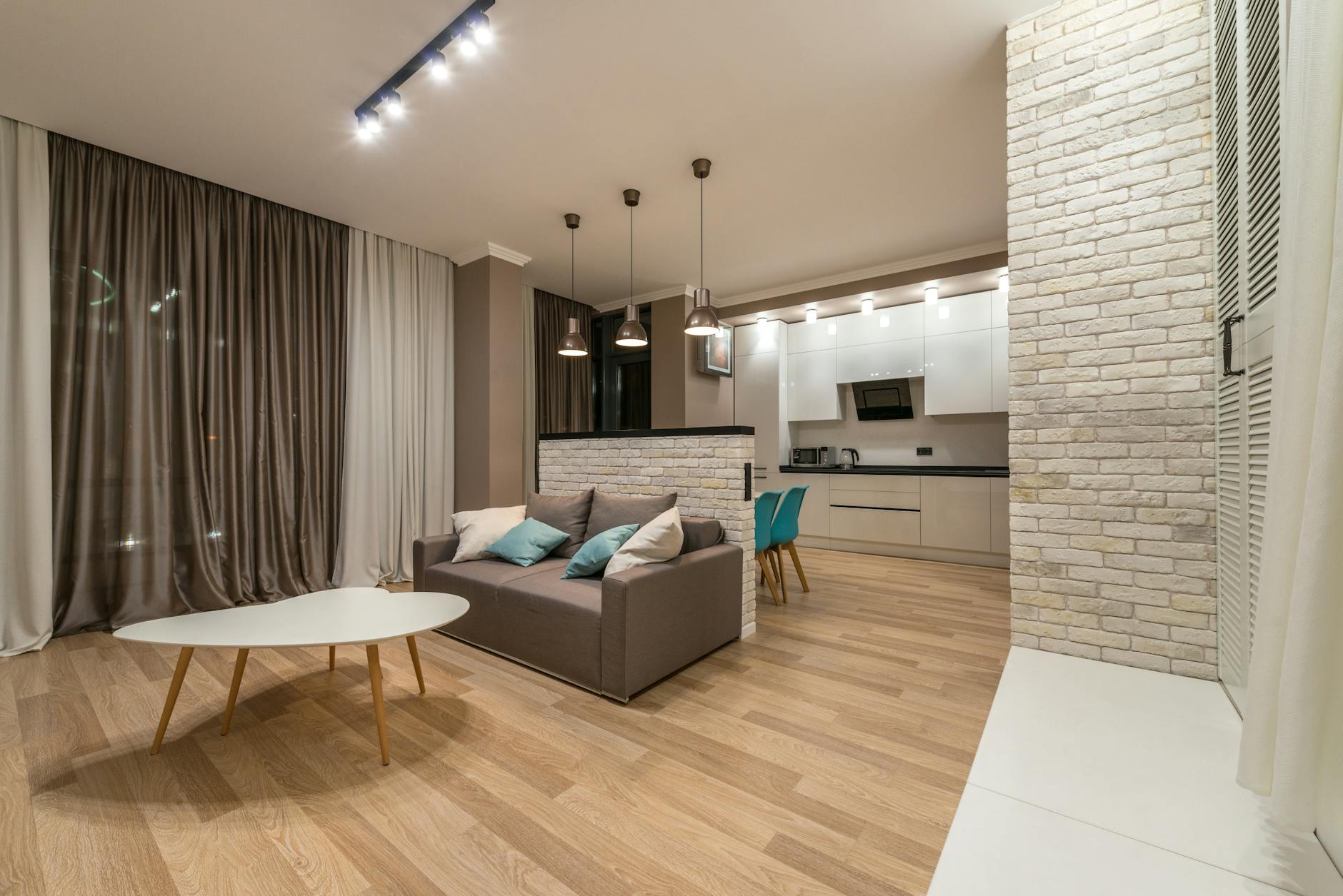 Salon z aneksem kuchennym, sofa i stół na tle nowoczesnej zabudowy